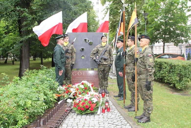 Zdjęcie przedstawia złożone kwiaty pod pomnikiem Golski