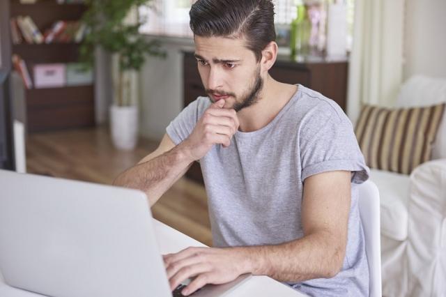Zdjęcie przedstawiające mężczyznę siedzącego przed ekranem laptopa